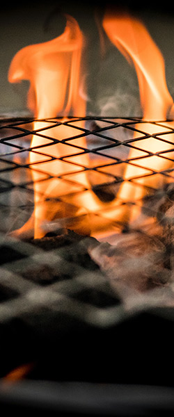 Fire on a grill while someone is practicing grilling safety.