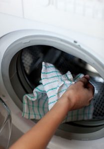 A person's hand getting clothes out of a dryer.