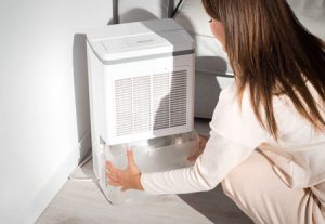 Woman taking measures to prevent black mold with a dehumidifier