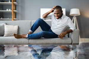 Man on sofa worried about flood vs water damage in home