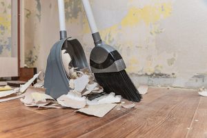 Cleaning debris in a home with a broom and dustpan