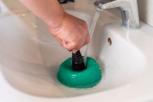 A person using a sink plunger to repair problems.