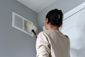 a woman dusting an air vent