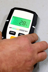 main using moisture meter to detect mold behind walls