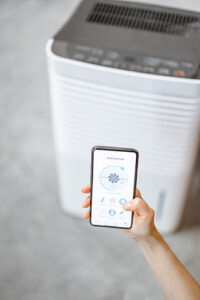 Person using their smartphone to control their dehumidifier to help with mold.
